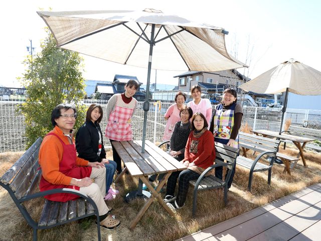 快適な屋外休憩スペース スタッフ 日差しや風を感じながら休息できる開放的な中庭です。スタッフと利用者の笑顔が印象的で、温かな雰囲気が伝わります。