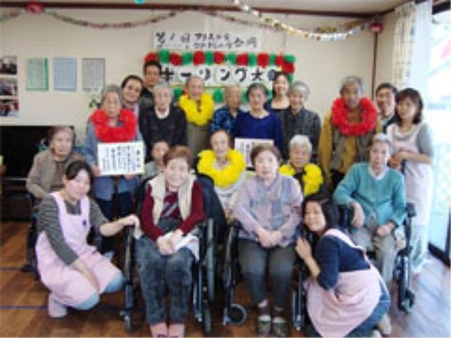 和やかな集合場面 イベント 笑顔あふれるスタッフと利用者様が一堂に会し、和気あいあいとした雰囲気を醸し出しています。あたたかみのある環境で、日々の業務に寄り添うことが期待できます。