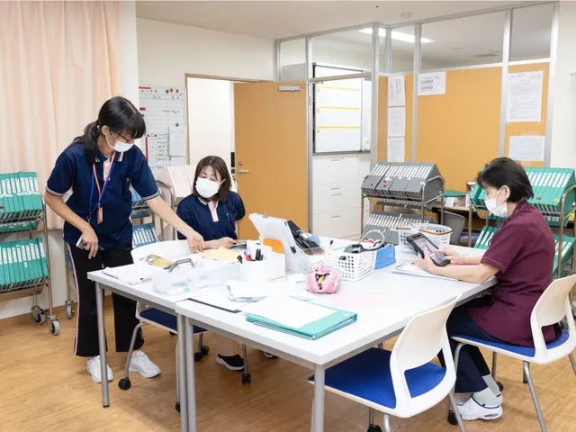 スタッフ業務の様子 スタッフイメージ スタッフが和やかに業務を行う空間です。整理された資料が効率的なサポートを支えています。
