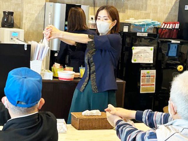 手を伸ばす住人たち スタッフイメージ スタッフが利用者と一緒に軽い体操を行っており、楽しく交流しながら健康を維持しています。