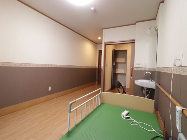 広々とした居室の様子 居室 床の木目調と落ち着いた色彩で統一された清潔感のある居室です。日々の生活に必要な設備が整っており、安心して過ごせる空間が広がっています。