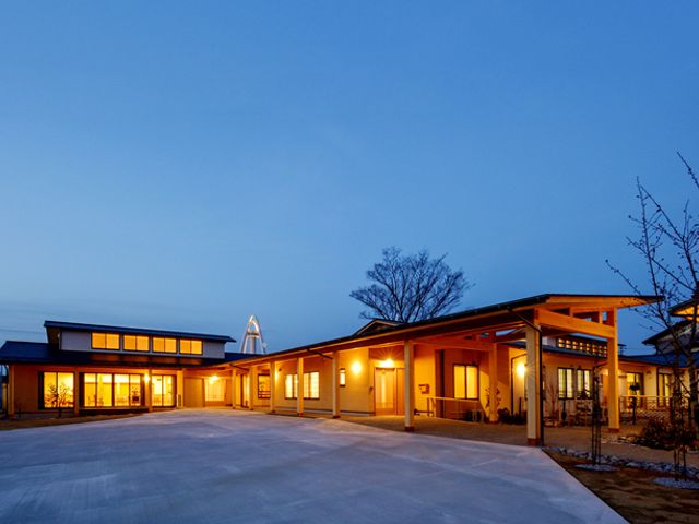 広がる建物の外観 外観 温かみのある照明が外観を優しく包む建物です。夕方の開けた空が静かに広がっています。