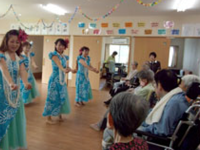 華やかなダンス披露の室内 多目的室 明るい多目的室で華やかなダンスが披露されています。利用者同士の交流も盛んです。