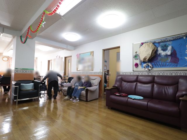 共有リビングの日常風景 リビング 快適なリビングでのひと時。椅子に座って会話を楽しむ方々や、穏やかに過ごす姿が見受けられます。