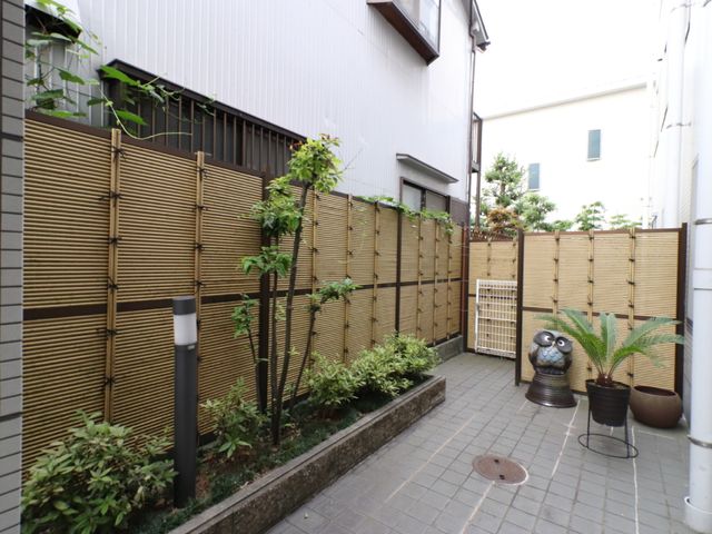 中庭の緑と装飾 玄関外 ゆとりのある中庭は、緑豊かで落ち着いた雰囲気を演出しており、憩いの時間を提供しています。