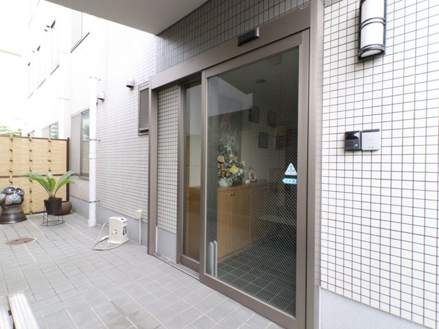 明るいエントランスの正面 玄関 明るく開放的なエントランスです。ガラス戸から見えるインテリアが、訪れる人々を温かく迎え入れます。