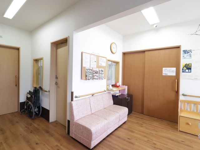 共有スペースの明るい角部屋 ホール 待合いかけのソファが置かれた休憩スペースです。壁には情報掲示板があり、椅子の配置もゆったりしています。