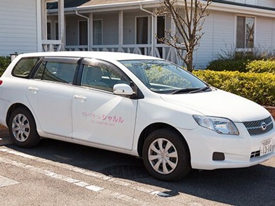 白い送迎車両と建物