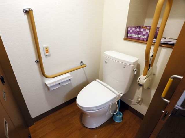 手すり付きトイレ設備 トイレ 安全に配慮された設計のトイレです。手すりや緊急呼び出しボタンが備えられ、利用者の快適さを考えています。