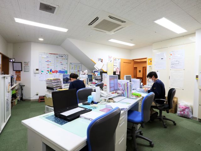 仕事中のスタッフの執務室 事務所 集中して仕事に取り組む職員の姿が見られる執務室です。様々な情報が掲示されており、連携を大切にしている環境がうかがえます。