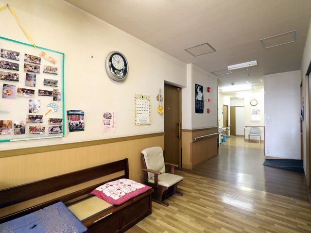 廊下の明るい情景 通路 廊下は広々としており、明るい雰囲気で、壁に飾られた写真や時計がアクセントになっています。利用者の皆様が快適にお過ごしいただける配慮がされています。