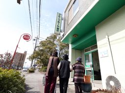 日差しの中、エントランス前に立つ人々