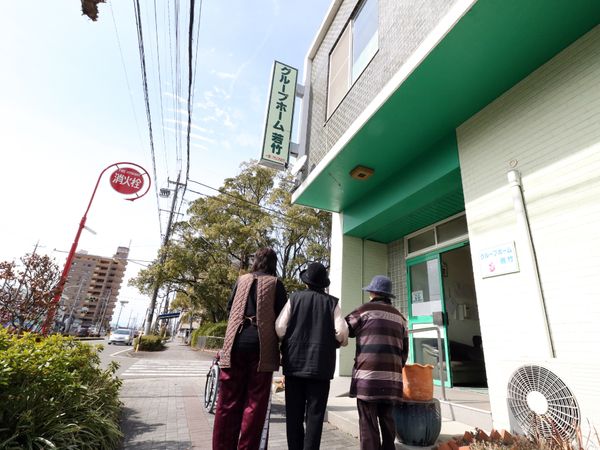 日差しの中、エントランス前に立つ人々