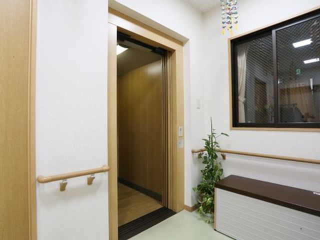 廊下の開いたドア エレベーター 廊下は清潔感があり、手すりが整備されており安全に考慮された造りです。ゆったりとした空間で働く環境が整っています。