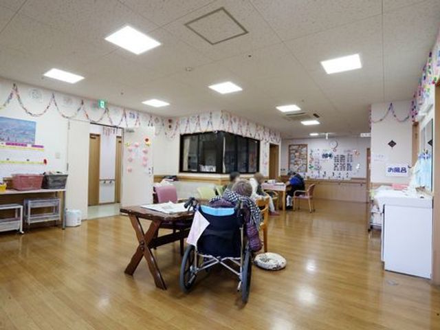 広々とした活動スペース 明るいフロアと装飾品 活動に集い交流する多目的室です。ゆったりとした椅子とテーブルが設けられ、利用者の方々がくつろいでいます。