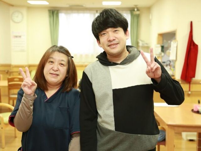笑顔のスタッフと利用者食堂 食堂   明るい食堂で、スタッフと利用者の方が並んで笑顔を見せています。和やかな雰囲気の中で、声かけや交流がしやすそうです。