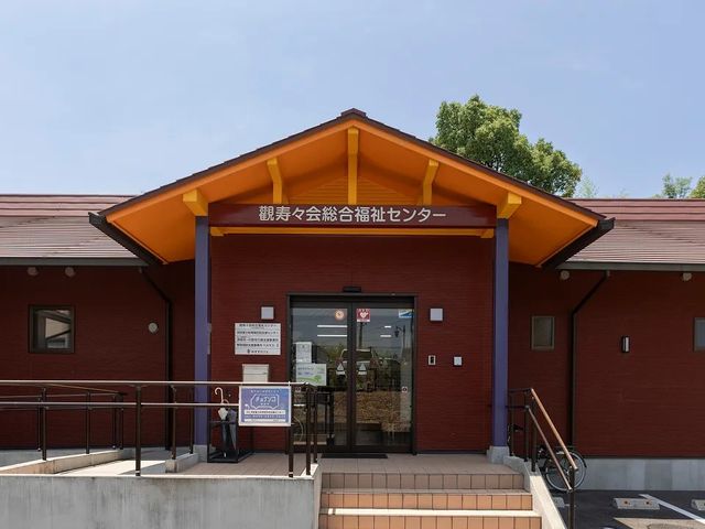 福祉センター玄関 外観   落ち着いた赤茶色の建物に、ひさしのある入口が印象的です。段差の少ない動線や手すりが見え、出入りしやすい工夫が感じられます。