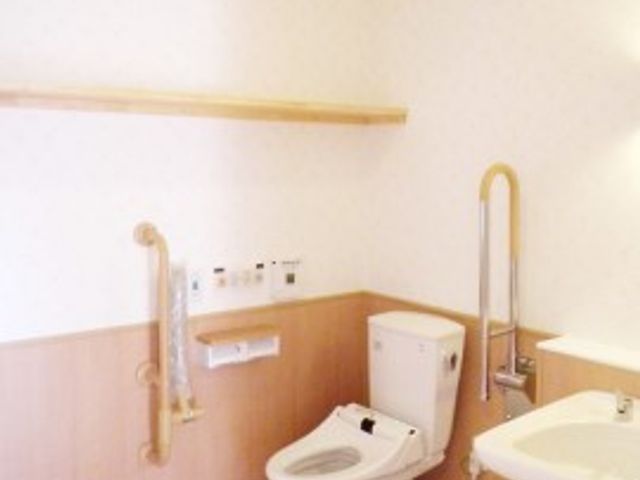 バリアフリー設計のトイレ トイレ 手すり完備で安全に配慮された清潔感のあるトイレ空間です。利用者の自立を支援し、安心して使える環境が整っています。