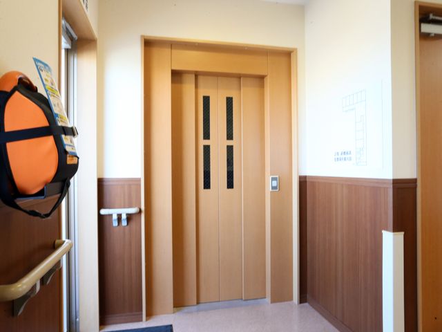 温かみのある廊下の扉 エレベーターホール 清潔感があり、広々として使いやすい扉が特徴の廊下です。職員や利用者さまの行き来もスムーズです。