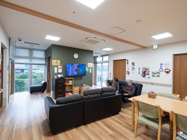 共用スペースと居住者 共有スペース ソファに座ってくつろぐ人々の和やかなラウンジです。テレビを見たり、手工芸に興じたりする穏やかな時間を過ごせます。
