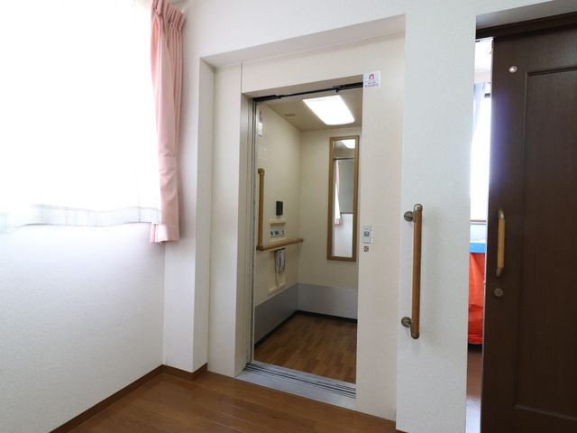 開いた扉のある廊下 エレベーター ゆったりとした通路はケアをするにあたって移動をしやすく設計されています。