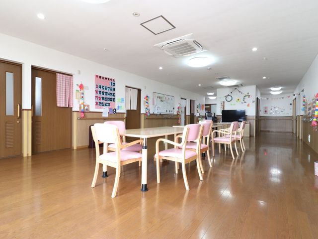 明るい共有スペース リビングダイニング 床の木目と調和した家具が特徴の食堂。壁には季節感ある飾り付けがされています。