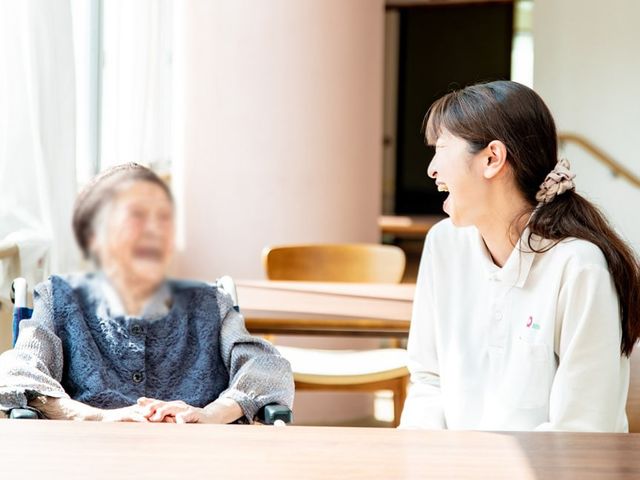 笑顔で過ごす職員と利用者のリビング リビング 自然光の入る広々とした空間で、職員と共に楽しいひとときを過ごせる場所です。