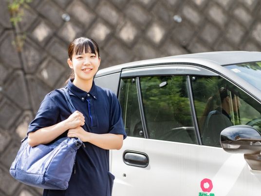 送迎車前の女性スタッフ  
