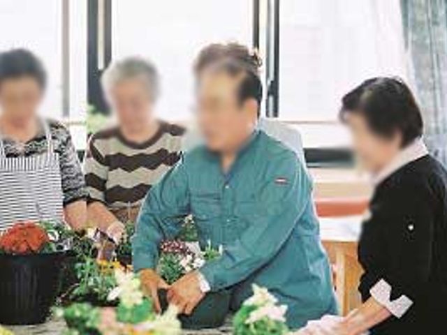 みんなで花を活ける様子の室内 内観 自然光が心地よい空間で、利用者と職員が和やかに花を活けています。協力し合う雰囲気が魅力的です。