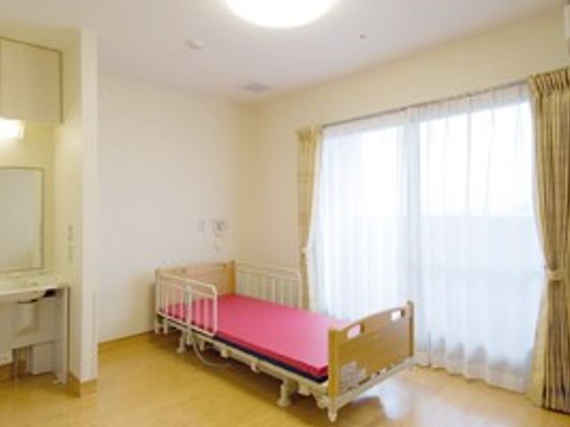 窓側にベッドがある居室 居室 大きな窓から自然光が差し込む明るい居室です。快適な環境で過ごしやすさを提供します。