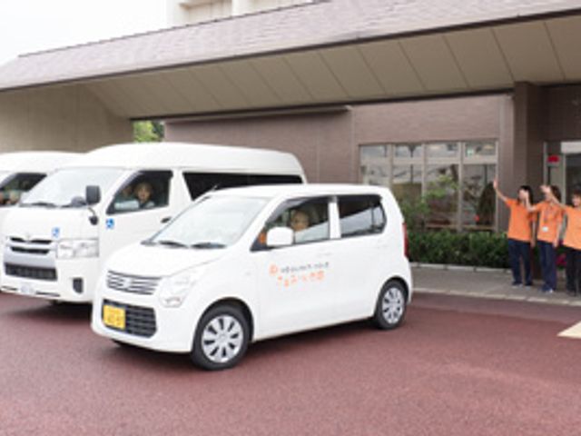 車両と職員の様子 外観 職員が整列し、迎えの車両と共にお出迎えする様子です。施設の外観です。