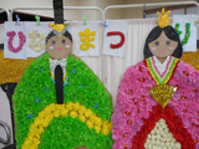 ひな祭りの飾り掲示物 掲示物 手作りのひな祭りの飾りが、彩り豊かに竹に掲げられており、利用者の創作活動の一環として楽しんでいる様子が伺えます。