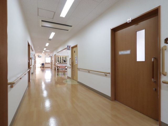 廊下の明るい風景 廊下 ゆったりとした廊下には、手すりが備え付けられており、安全に配慮された設計です。向こうに見える方が笑顔でくつろいでいる様子が伝わります。