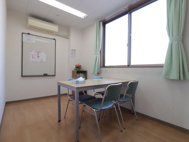 明るい会議室の一角 談話室 シンプルで清潔感のある多目的室は、集まりや活動の場としてご利用いただけます。窓辺の光が心地よい空間です。