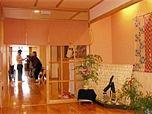 和やかな廊下の様子 廊下   暖かな色合いの廊下では、スタッフが利用者と共に歩く様子が見られ、親しみやすい雰囲気です。