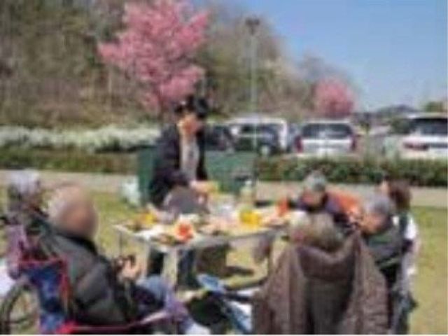 桜の下での食事風景 外出イベント 桜満開の温かな日差しの下、笑顔で会話を楽しむ皆様の姿。リラックスした時間があなたを待っています。