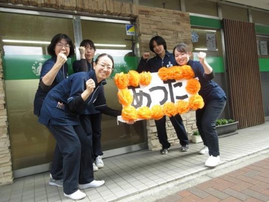 スタッフが看板を持つ外観  