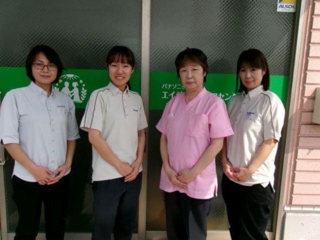 スタッフが並ぶ玄関前 エントランス   スタッフの皆さんが玄関前に並んでいます。明るく整った出入口で、働く雰囲気が伝わります。