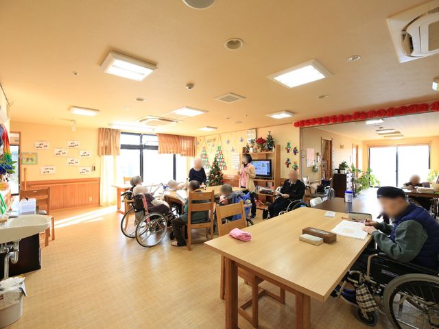 明るい共有スペース リビング 広々とした食堂では利用者がゆったりと過ごしています。窓から自然光が差し込み、温かな雰囲気です。