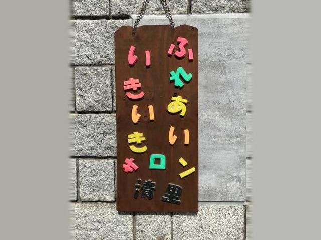 ふれあいロビーの看板 ロビー   木製の看板に、色とりどりの文字で施設名が並んでいます。あたたかい雰囲気があり、来訪者を迎えやすい印象です。