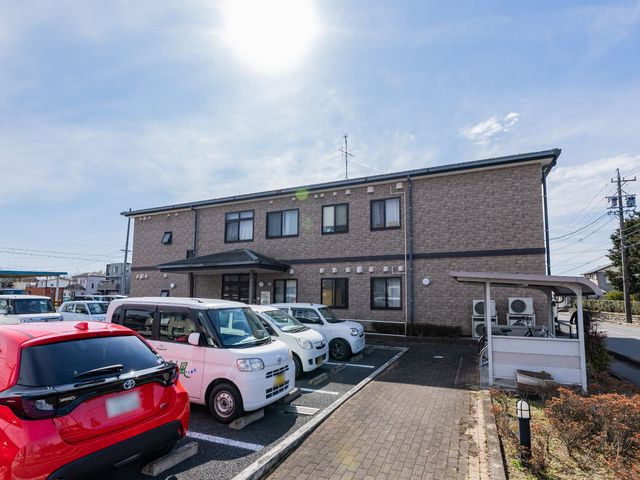 施設の外観と駐車場 外観 広々とした駐車スペースがある落ち着いた色合いの建物です。移動に便利な立地でお待ちしています。