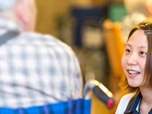 会話を楽しむ様子の場面 リビング 明るいリビングで職員と入居者が笑顔で会話を楽しんでいます。温かい雰囲気が広がる空間です。