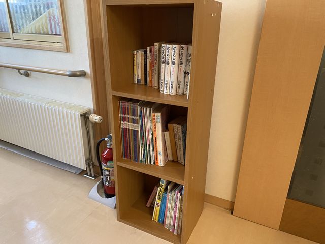 本棚と消火器の廊下 廊下 廊下に備えられた本棚には多彩な書籍が揃っており、読書を通じて心豊かな時間を過ごせる工夫が感じられます。