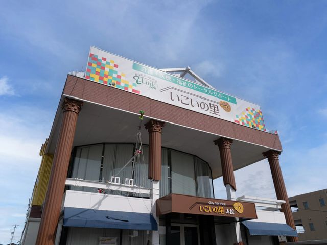 施設の外観 外観   青空の下に、柱が並ぶ印象的な建物です。看板には事業名が大きく表示され、明るい雰囲気が伝わります。