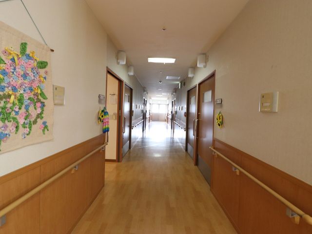 明るい廊下のイメージ 廊下 廊下は木目調で温かみがあり、壁には手作りの装飾が飾られています。清潔感にあふれ、歩行のサポートに配慮した手すりも設置されております。