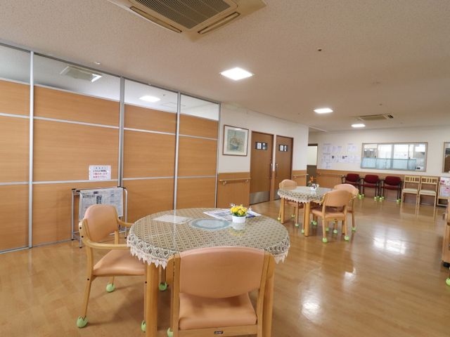 共用スペースの快適な居場所 玄関ホール やわらかな光が差し込む温かみのあるラウンジです。ゆったりと会話が楽しめる配置のテーブルと椅子が印象的です。