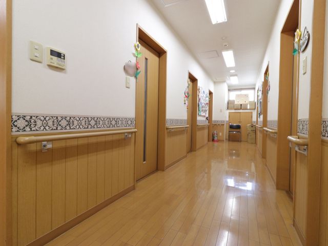 明るい清潔な廊下 廊下 ゆったりとした廊下には、手すりが設置されており安全に配慮されています。壁には飾りがあり、温かみのある雰囲気を演出しています。