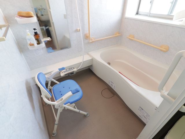 バリアフリー浴室設備 お風呂 身体の不自由な方も使いやすい、手すり付きの浴槽とシャワーチェアが設置された浴室です。快適な入浴のための配慮が行き届いています。