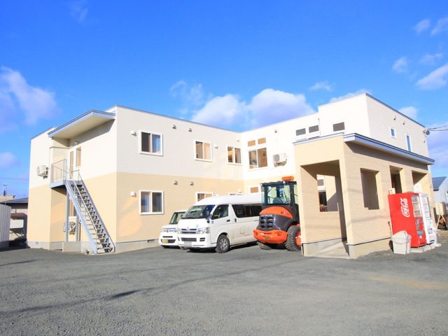明るい外観の建物 外観 広々とした駐車スペースがあり、日当たりの良い快適な環境です。賑やかな雰囲気の中で、充実した職場生活を送ることができそうです。