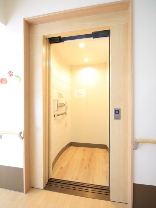 施設館内に完備されているエレベータである。扉は開かれ、庫内に設置されている手すりや2台のインターホンが見える。